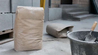 Unbedruckter Zementsack neben Mörtelkübel und Kelle auf einer Baustelle